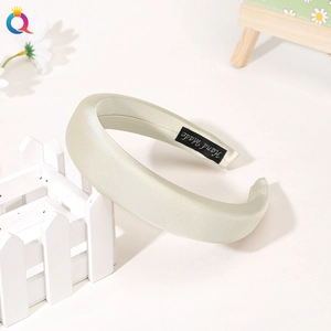Detailed close-up of a wide cream satin headband with elegant handmade inner label