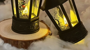 Detail of black Halloween LED lantern with witch and skull designs on wood base