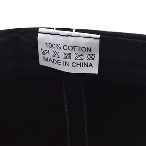 Close-up of wash care label showing 100% cotton fabric and icons on baseball cap