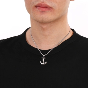 Detail of silver anchor pendant on twisted chain worn by model on black t-shirt