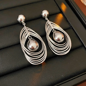 Polished silver tiered hoop drop earrings with teardrop pendant on black display pad