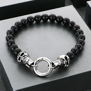 Détail d'un bracelet en perles avec breloques tête de mort en argent et grand fermoir