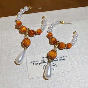 Detail of vintage French style earrings with teardrop pearls and textured orange beads