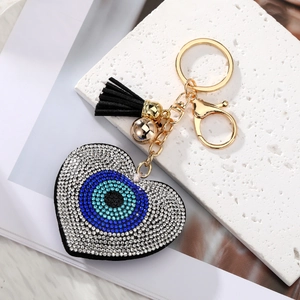 Macro shot of evil eye heart keychain with blue crystals, gold ring and black tassel