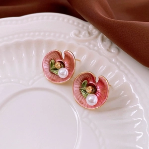 Detailed macro view of pink enamel flower earrings with pearls on a ceramic tray