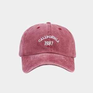 Detail of embroidered California 1987 logo on a washed red cotton baseball cap