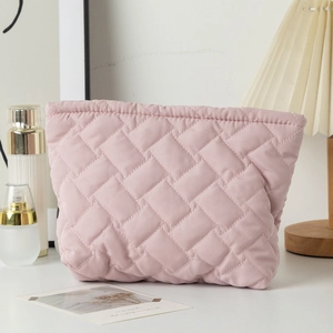 Close-up of pink quilted fabric cosmetic bag with textured woven pattern and top zipper