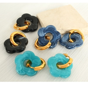 Detail of floral resin hoop earrings in black and blue with golden metal finish