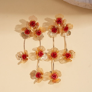 Détail de boucles d'oreilles fleurs en maille dorée avec roses rouges et franges