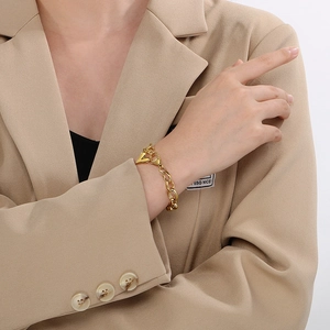 Close-up of 18K gold plated oval link chain bracelet with a heart pendant on wrist