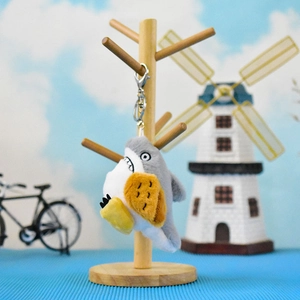 Detailed view of a funny plush shark keychain with grey and white fur on a wooden stand