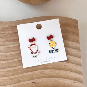 Detail showing asymmetric Santa Claus and striped candle earrings with red bows