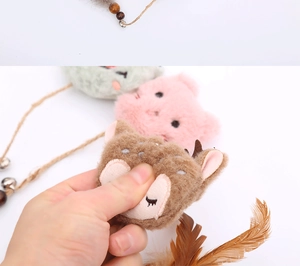 Detail of plush cat toy showing the soft texture of stuffed animal heads with bells and feathers