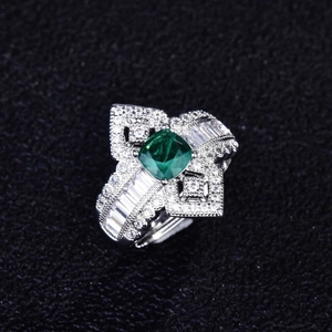 Detail of emerald cut green gemstone ring with micro-pave diamonds on black background