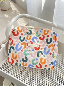 Detailed view of colorful quilted floral makeup bag with Sosokka tag and beige zipper