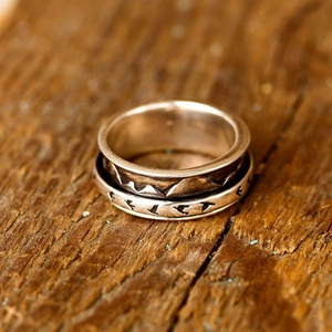Macro shot of rotatable vintage silver ring featuring mountain texture and bird silhouettes