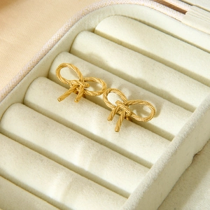 Pair of delicate gold bow earrings in a beige jewelry box with 18K gold plating