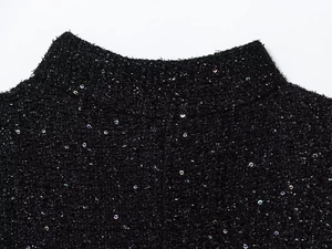Nahaufnahme des schwarzen Tweed-Ausschnitts mit bunten Pailletten und feinem Strick