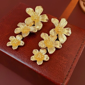 Macro shot of vintage gold flower tassel earrings on a brown leather texture background