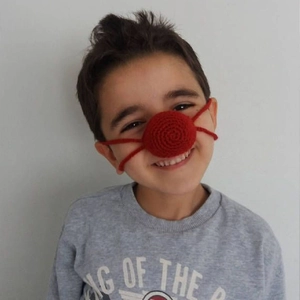 Close-up of a red handmade crochet nose warmer with ties for kids Halloween party