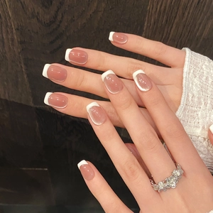 Detail of French press-on nails with nude pink base and white tips on model hand