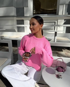 Pink crewneck knitted sweater and leather handbag set in a bright outdoor street scene