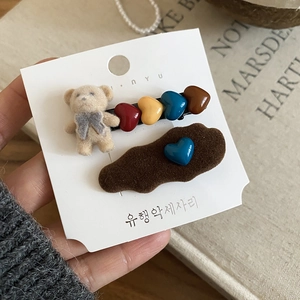 Close-up of flocking bear and heart hair clips on card, showing soft plush texture