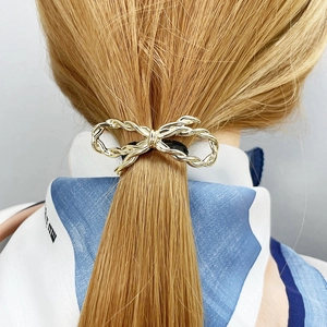 Elegant golden twisted bow hair clip on a ponytail for minimalist women hair styling