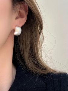 Close-up of minimalist matte silver crescent earrings worn by model with metallic finish