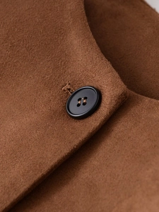Gros plan d'une veste en daim marron avec un détail de bouton noir à quatre trous