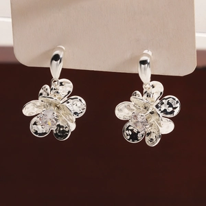 Detailed view of silver flower earrings with hammered metal petals and zircon center
