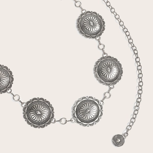 Detailed macro view of vintage silver metal waist chain with engraved concho discs
