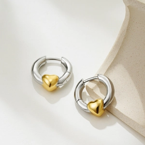 Detailed close-up of two-tone heart hoop earrings with silver rings and gold hearts