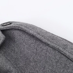 Detailed close-up of shoulder seam and black button on a grey wool coat with rich texture