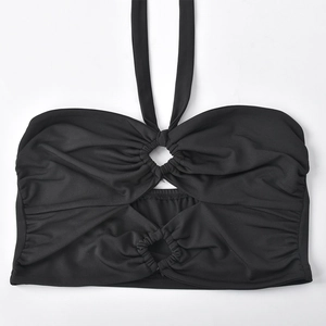 Detail of black halter crop top with central hollow metal ring and pleated design