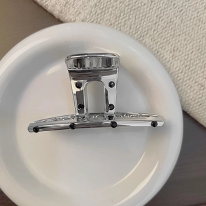 Pince à cheveux en métal argenté avec strass noirs sur une assiette blanche