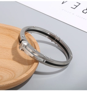 Industrial carbon fiber and stainless steel bracelet on a minimalist wooden tray