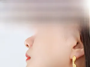 Gros plan d'un mannequin portant des boucles d'oreilles géométriques irrégulières