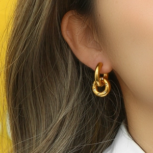Golden double interlocking hoop earrings with sparkling diamonds on a female model