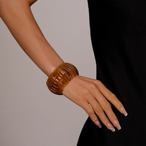 Détail d'un bracelet vintage en acrylique ambré avec une texture épaisse nervurée