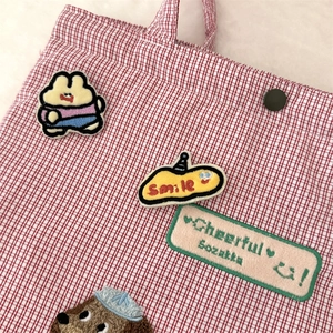 Close-up of red checkered canvas pouch featuring cute cartoon rabbit and smile embroidery