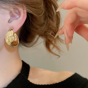 Close-up of golden twisted spiral earrings on model for a modern minimalist style
