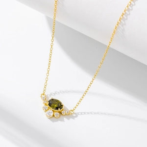 Close-up of gold oval olive green zircon pendant with sparkling clear accent stones