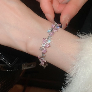Sparkling pink heart zircon bracelet on a wrist with a soft white sleeve close-up