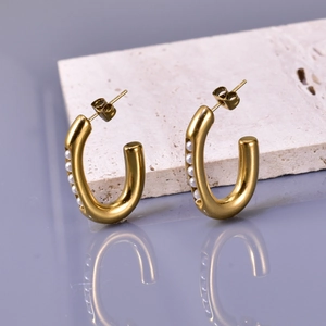 French style U-shaped stainless steel earrings with white pearls on a stone background