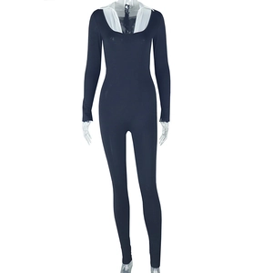 Dettaglio tuta lunga blu navy con scollo a U bianco, zip e vestibilità aderente elegante