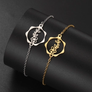 Detailed close-up of hollow flower pendants in silver and gold on a matte black stand