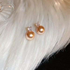 Macro shot of elegant champagne pearl stud earrings with sparkling cubic zirconia inlay