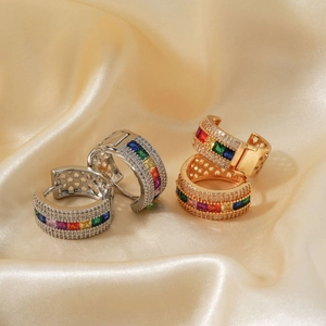 Close-up of luxury hoop earrings with rainbow square zircon and pave crystals on silk