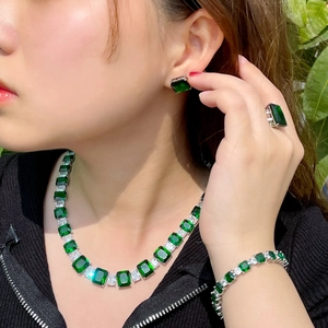 Détail d'un ensemble de bijoux en argent avec pierres carrées vertes sur un mannequin